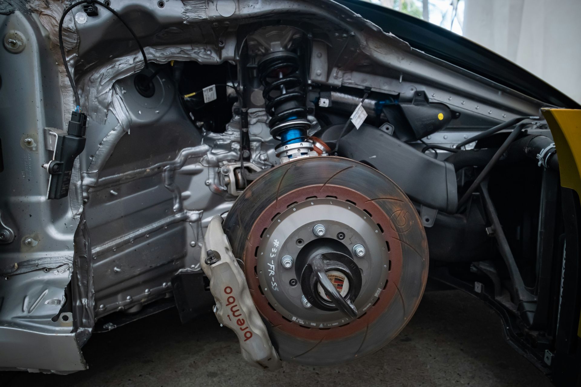 Car front suspension, brake disc, and caliper exposed.